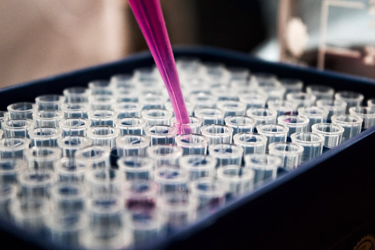 A laboratory pipette filling a tray of clear sample wells, used to illustrate a computer science research release.