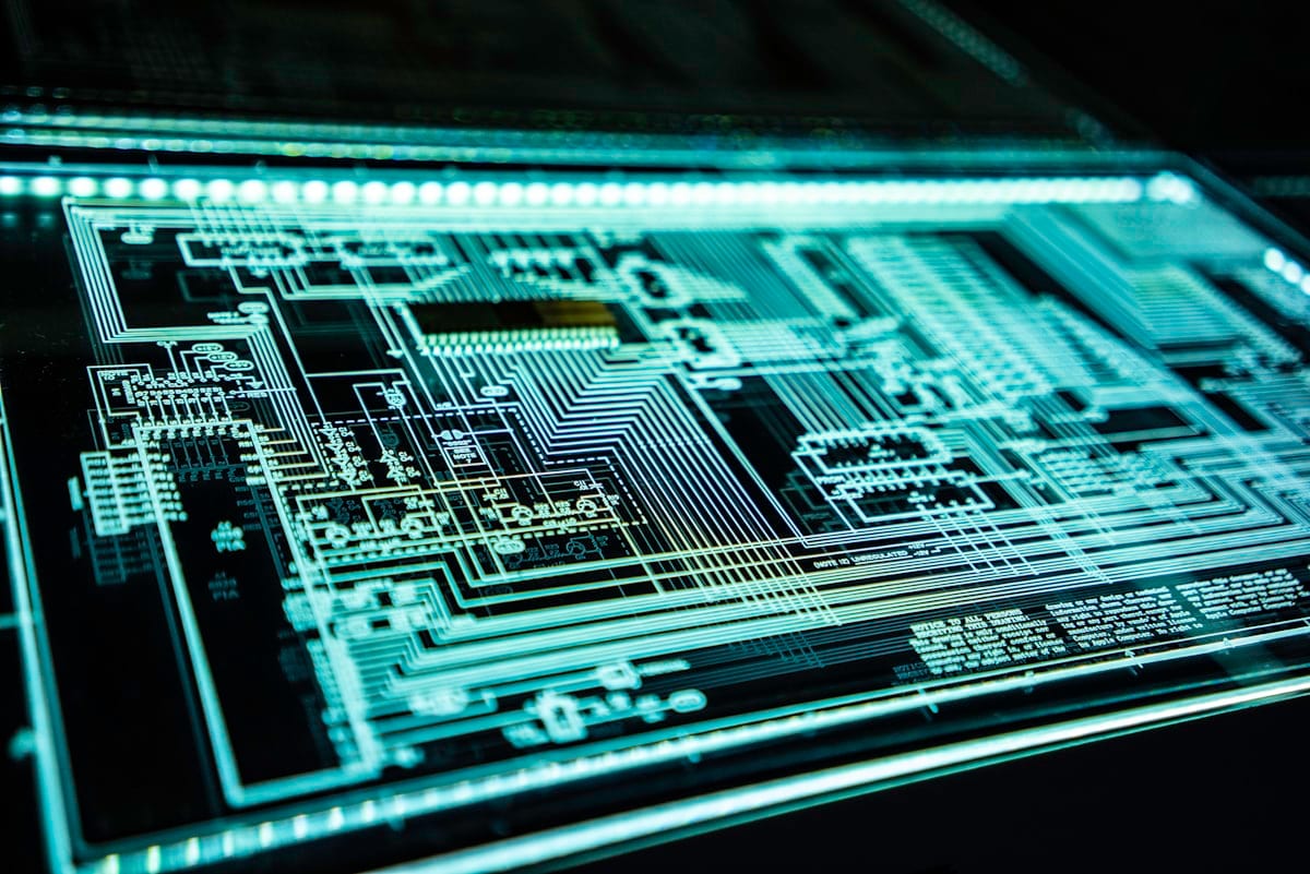 A close-up of a circuit board displayed in cool blue light, representing the infrastructure behind open-weight AI.
